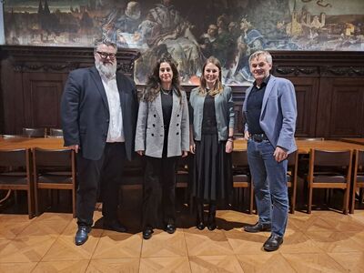 Die zwei DB-Leiterinnen Aslihan Gebhart und Christine Pfisterer stehen gemeinsam mit dem zweiten Bürgermeister Andreas Rother und Wirtschaftsreferent Werner Lang vor einem Wandgemälde im Rathaus in Passau.
